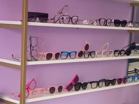 Prateleiras com armações coloridas — rosa, azul e tons claros — ao lado de modelos escuros.