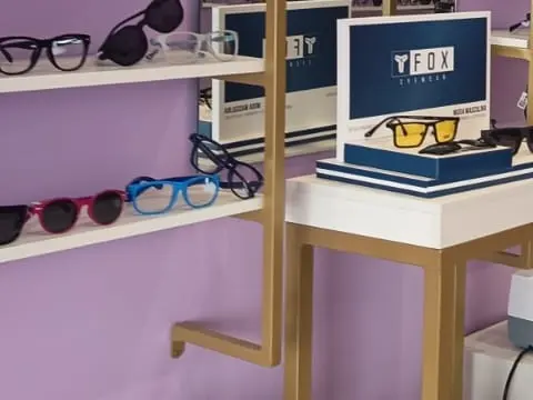 Display da Fox Eyewear com armações azuis e vermelhas expostas na prateleira.